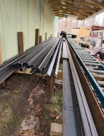 Metal fencing rails and posts stacked on a trailer for transport.